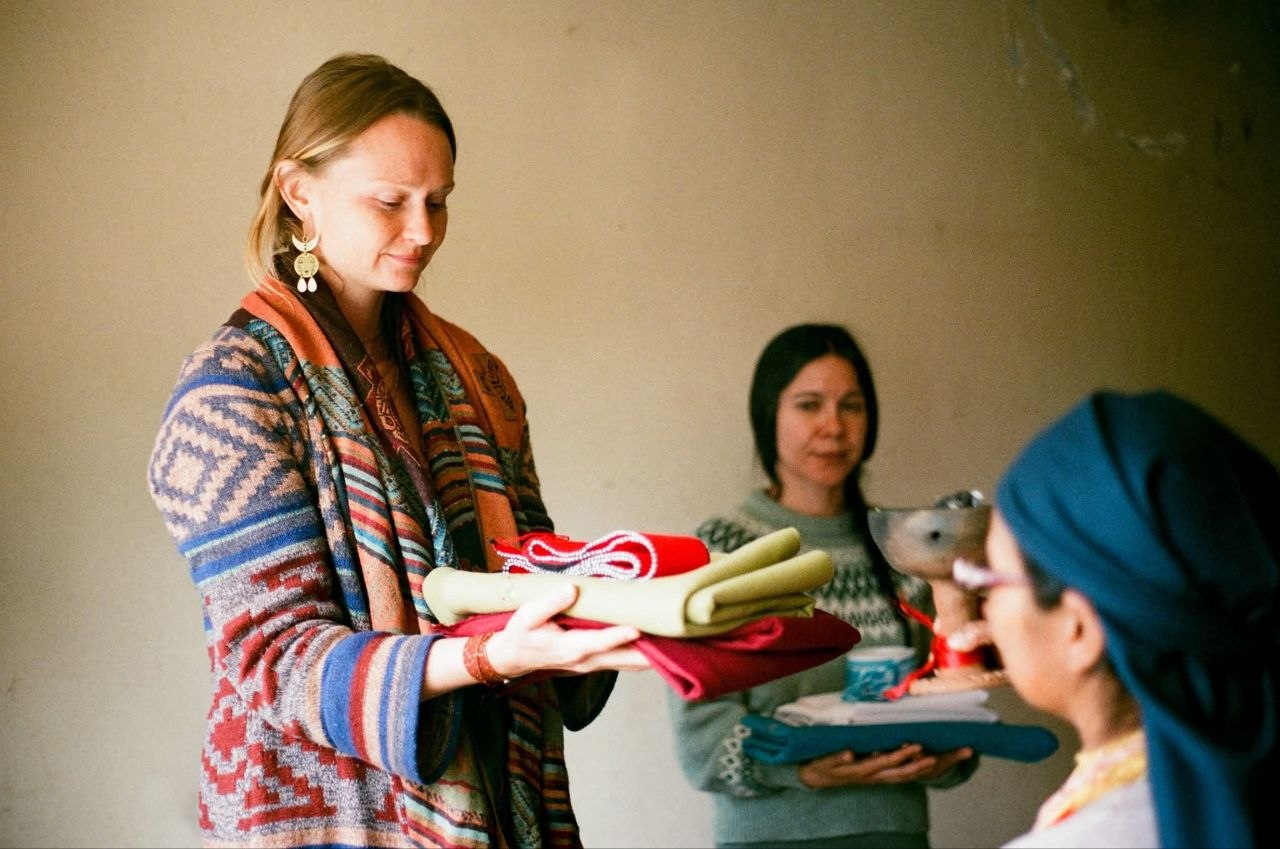 Kelli passing folded ceremonial cloths during training