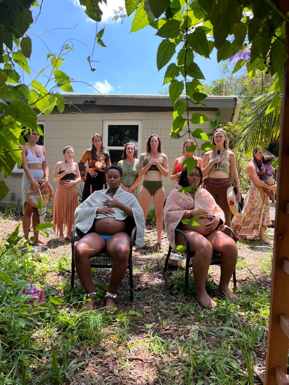 Circle of mothers gathering outdoors to honor two pregnant women