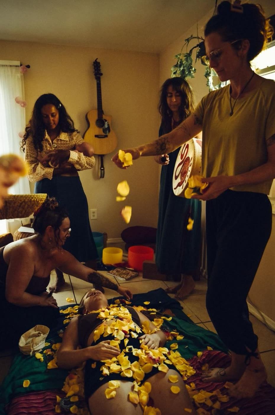 Postpartum ceremony — women gathering to honor a new mother with flower petals